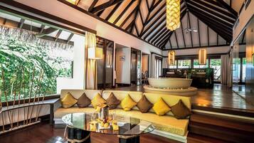 A spacious living area with a sofa, a glass coffee table, and a ceiling fan.