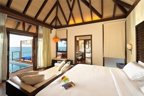 A hotel room with a large bed, a small seating area with a view of the sea, and a separate dining area. - Coco Bodu Hithi (Bodu Hithi)