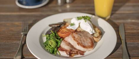 A plate of food with a cup of coffee and a glass of orange juice on a wooden table.
