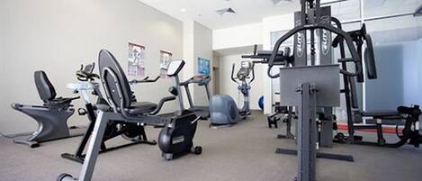 Une salle de sport équipée de divers appareils d’exercice, notamment des tapis de course et des appareils de musculation elliptique.