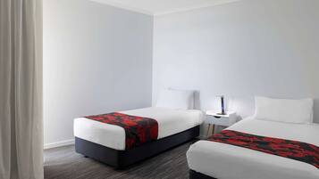 A hotel room with two beds, a nightstand, and a lamp.