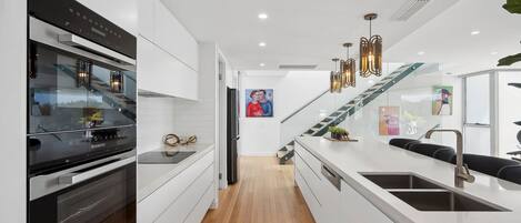 A modern kitchen with white cabinetry, stainless steel appliances, and a wooden floor.