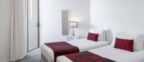 A hotel room with two beds, a nightstand, a lamp, and a sliding door.