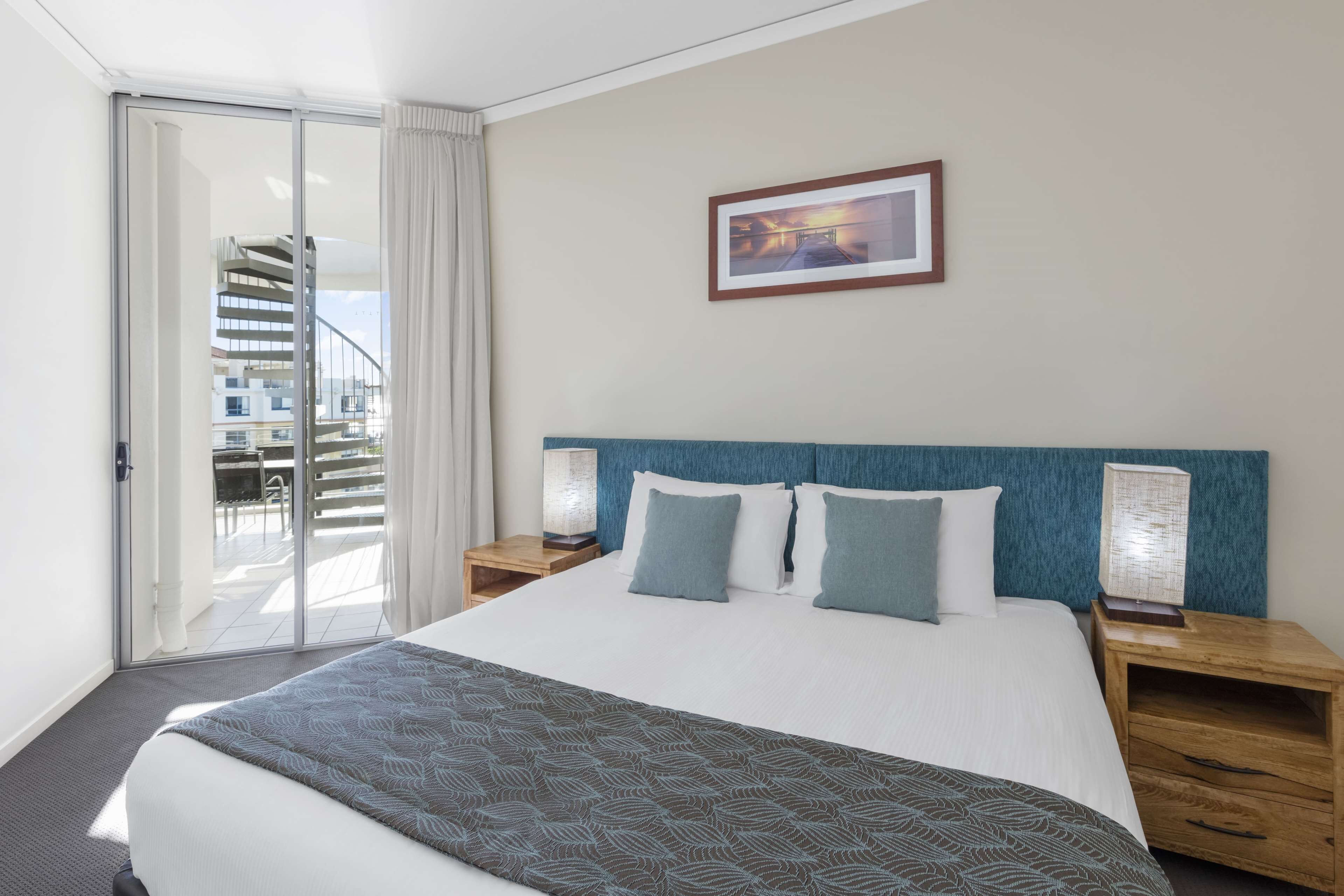 Habitación de hotel con una cama grande, vistas a una escalera de caracol y un cuadro en la pared.