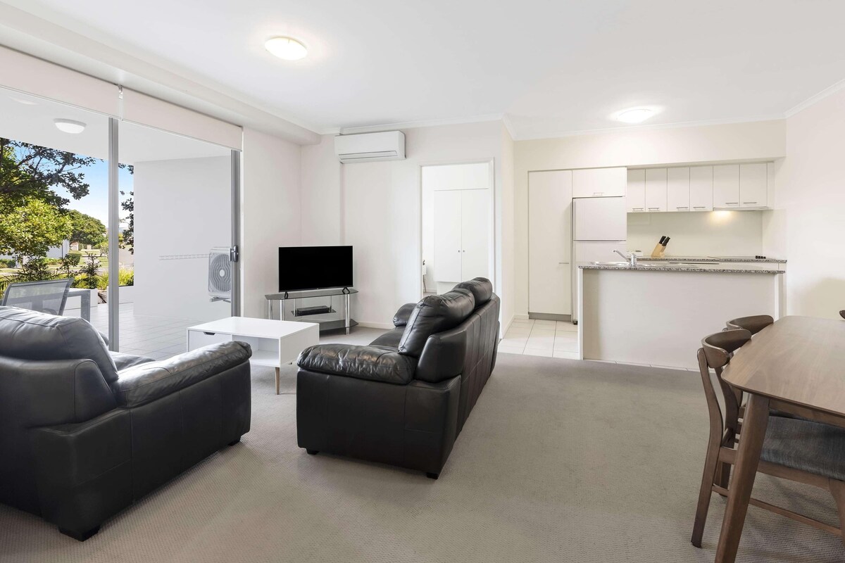Una sala de estar moderna con un televisor de pantalla plana, sofás de cuero, una mesa de centro y una zona de comedor con una mesa y sillas de madera.