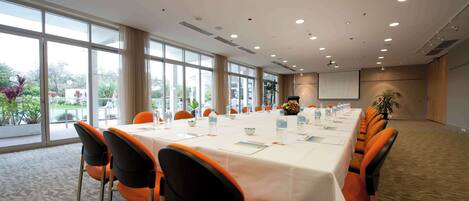 A conference room with a long table, chairs, and a projector screen.