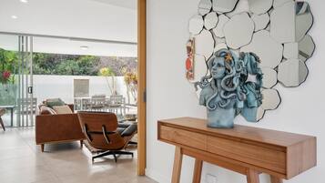 Un salon moderne avec un canapé, des fauteuils, une table basse en bois et une œuvre d’art murale.