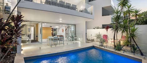 Una piscina al aire libre, sombrillas, sillones reclinables de piscina