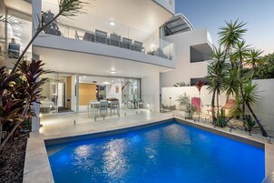 Una piscina al aire libre, sombrillas, sillones reclinables de piscina