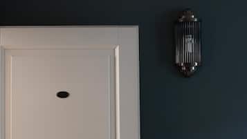A closed white door with a keyhole and a doorknob, a wall-mounted light fixture, and a dark blue wall.