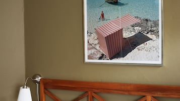 Un dormitorio con cabecera de madera, un cuadro con una playa y una lámpara de noche.