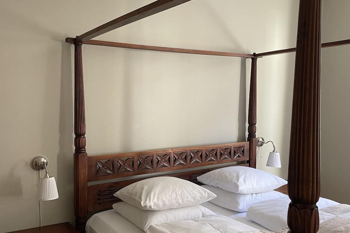 A four-poster bed with a wooden headboard and a quilted bedspread.