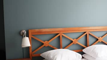 A neatly made bed with white linens, a wooden headboard with a crisscross design, and a bedside table with a lamp.