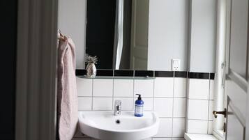 Un baño con un lavamanos blanco, un espejo y una toalla colgada en la pared.