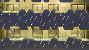 Fachada de edificio con un diseño geométrico de paneles hexagonales, algunos con plantas.