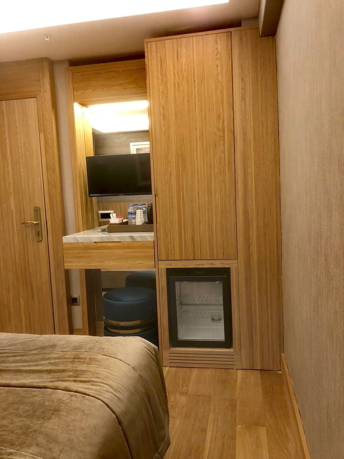 Ein kleines Zimmer mit Bett, Küchenzeile, Fernseher und kleinem Kühlschrank.
