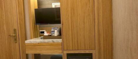 Ein kleines Zimmer mit Bett, Küchenzeile, Fernseher und kleinem Kühlschrank.