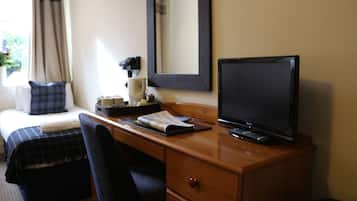 Habitación de hotel con una cama, un escritorio con computadora, una silla y un espejo.