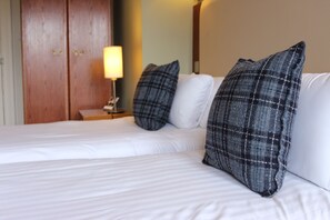 Ein Hotelzimmer mit zwei Betten, einem Holzschrank und einer Nachttischlampe.