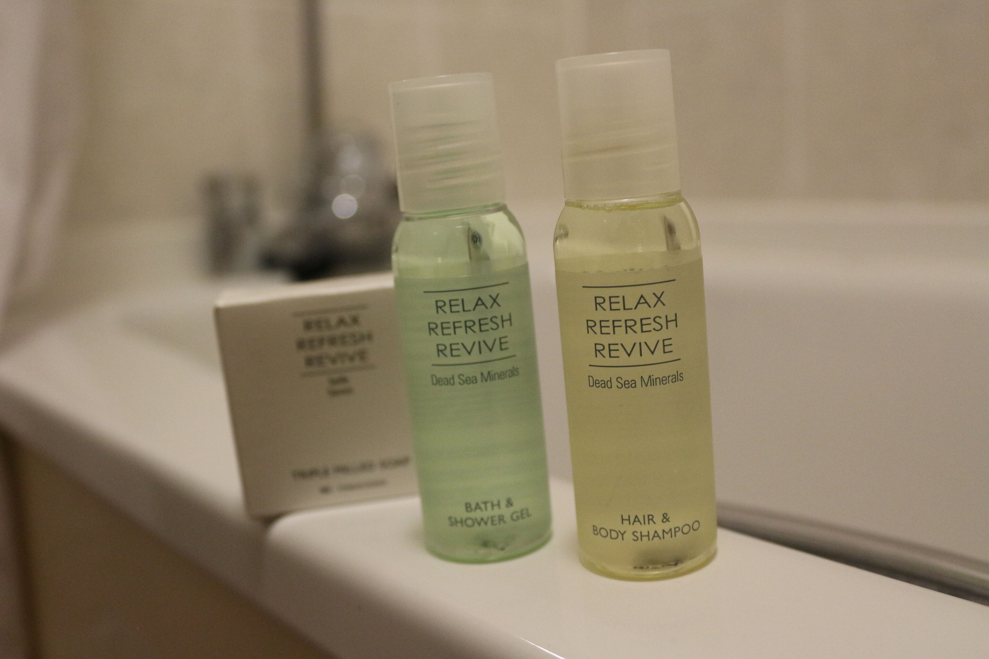 Two bottles of 'Relax Refresh Revive' Dead Sea Minerals bath and shower gel and hair and body shampoo on a shelf.