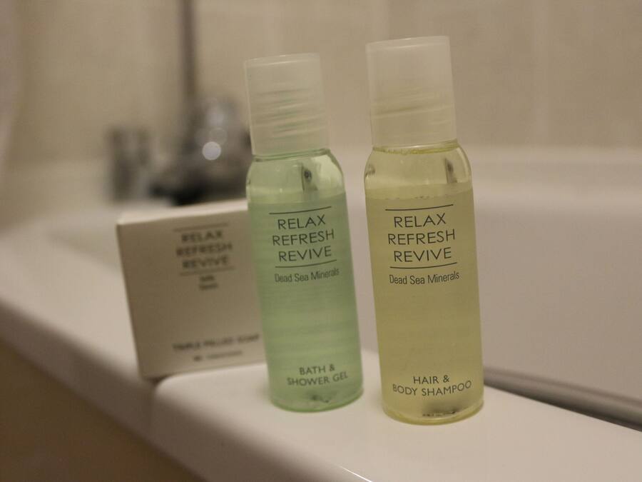 Twee flessen 'Relax Refresh Revive' bad- en douchegel en haar- en body shampoo staan op een plank.