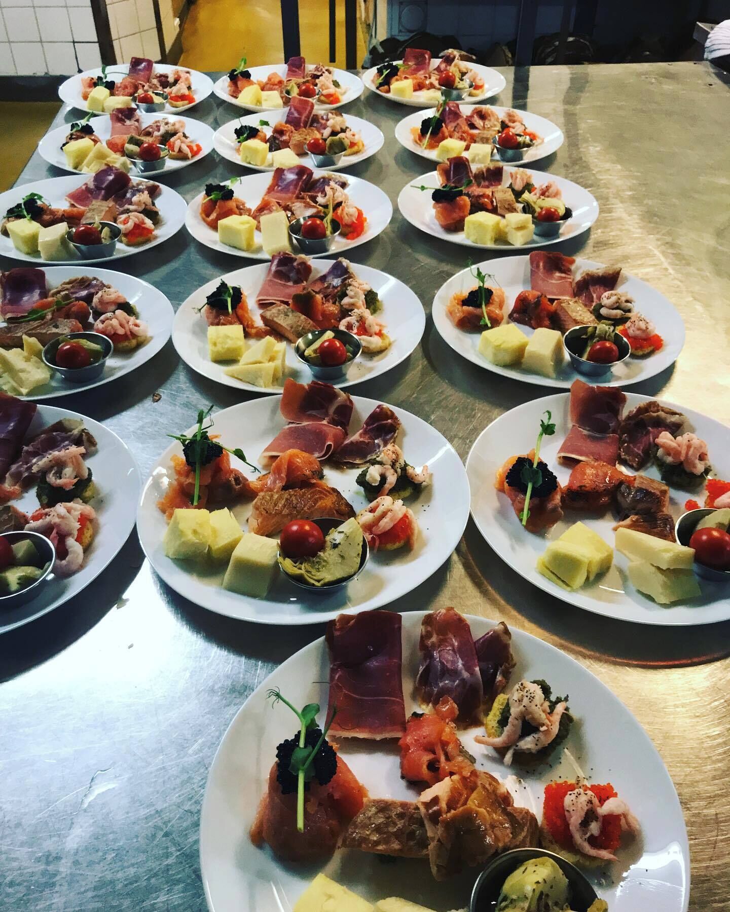 Una mesa con varios platos de aperitivos variados, incluyendo carnes, quesos y verduras.