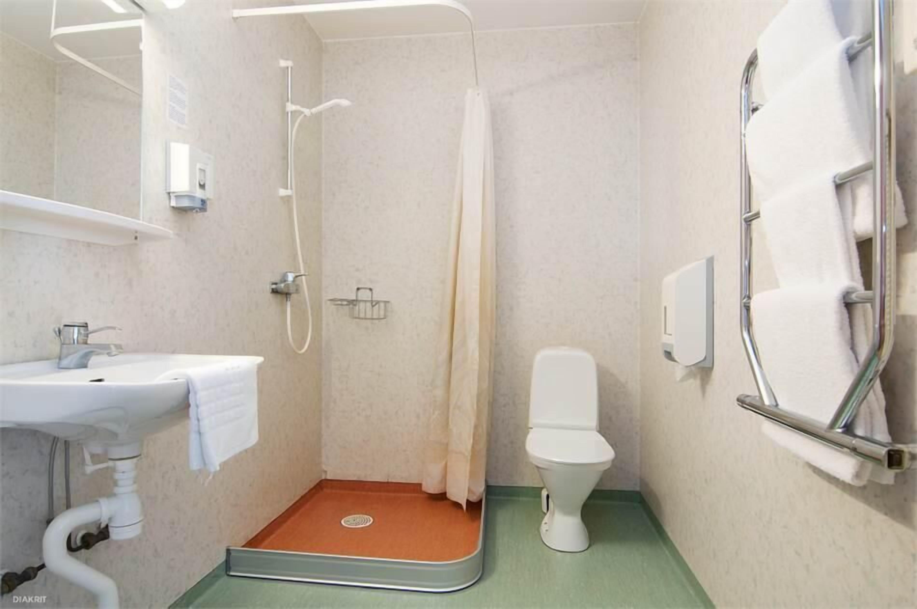 Un baño pequeño con ducha, inodoro y lavamanos.