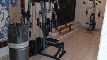 A gym with various exercise equipment, including a punching bag labeled "TITANIUM BY HAMMER".