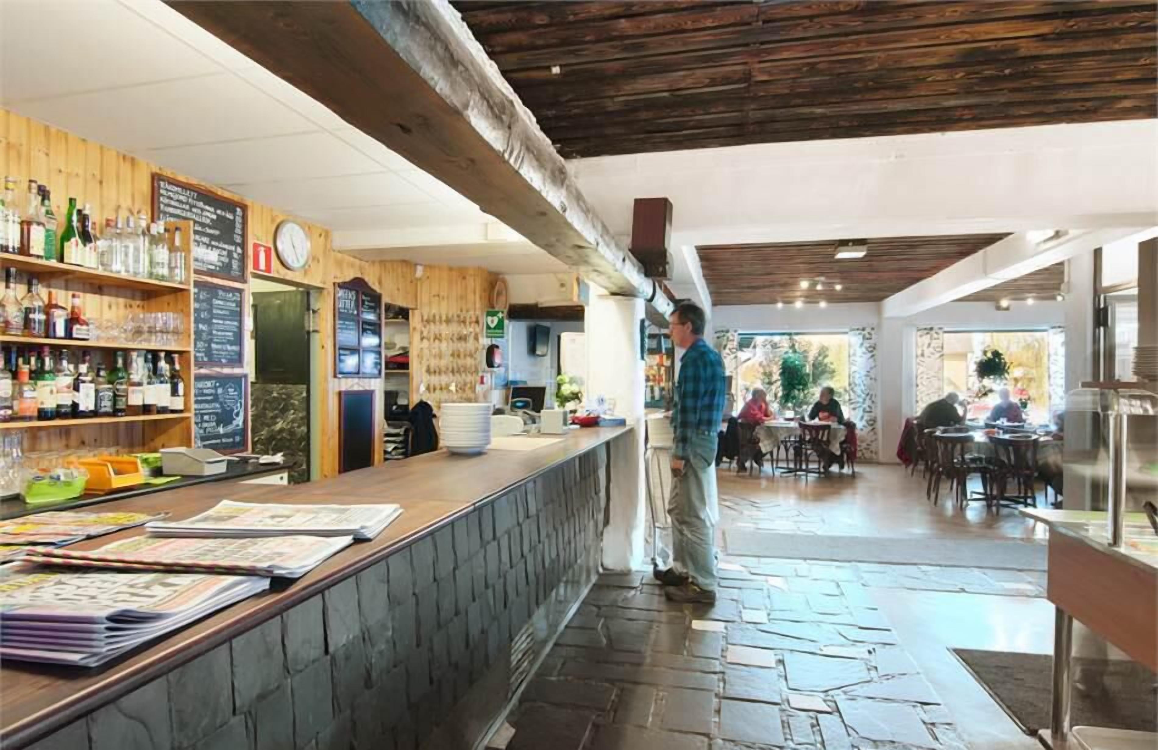 A bar area with wooden shelves, a clock, and a counter with menus.