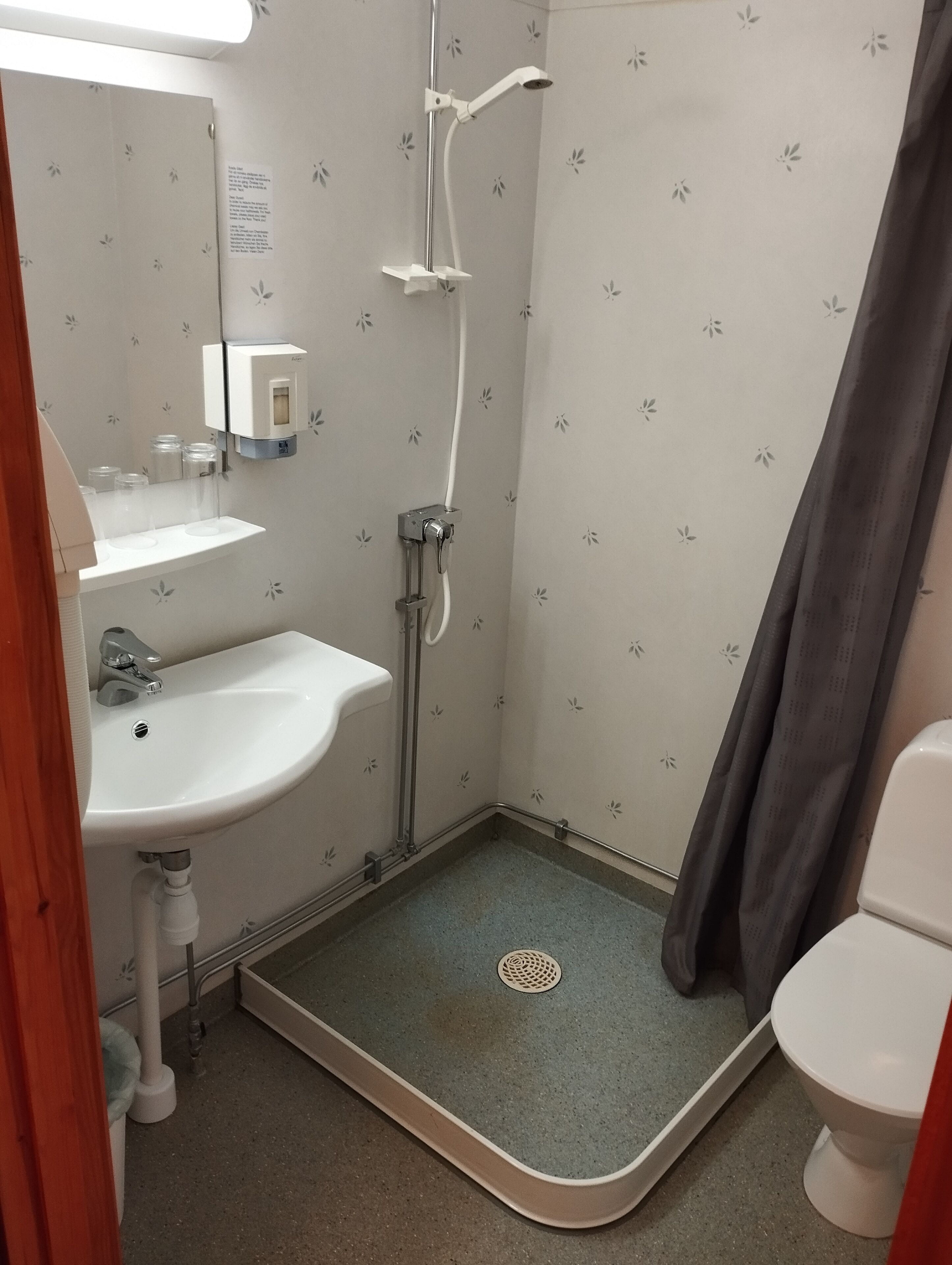 Un baño pequeño con ducha, lavabo e inodoro.