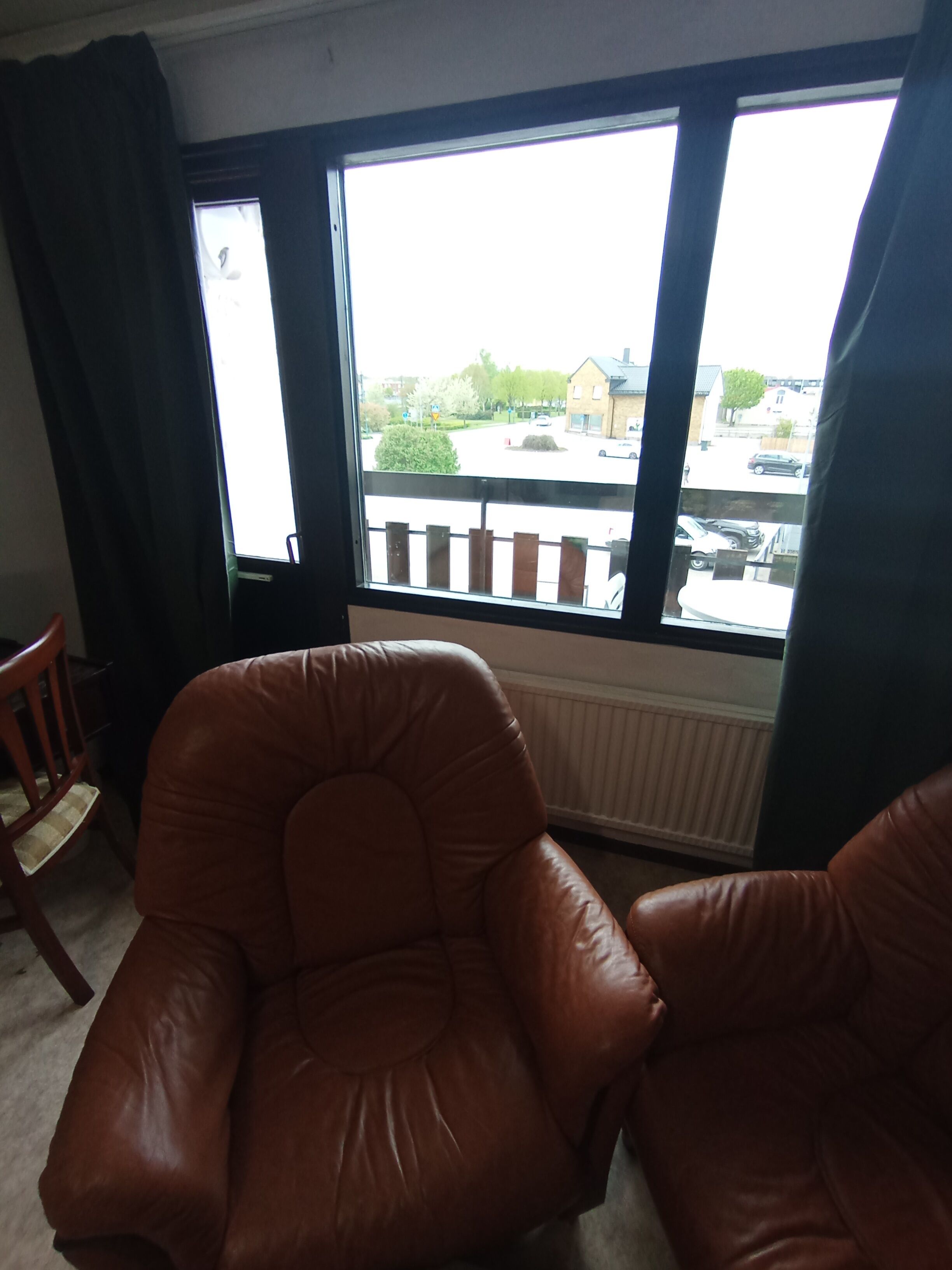 Una habitación con un ventanal grande, un sillón de cuero marrón y un radiador.
