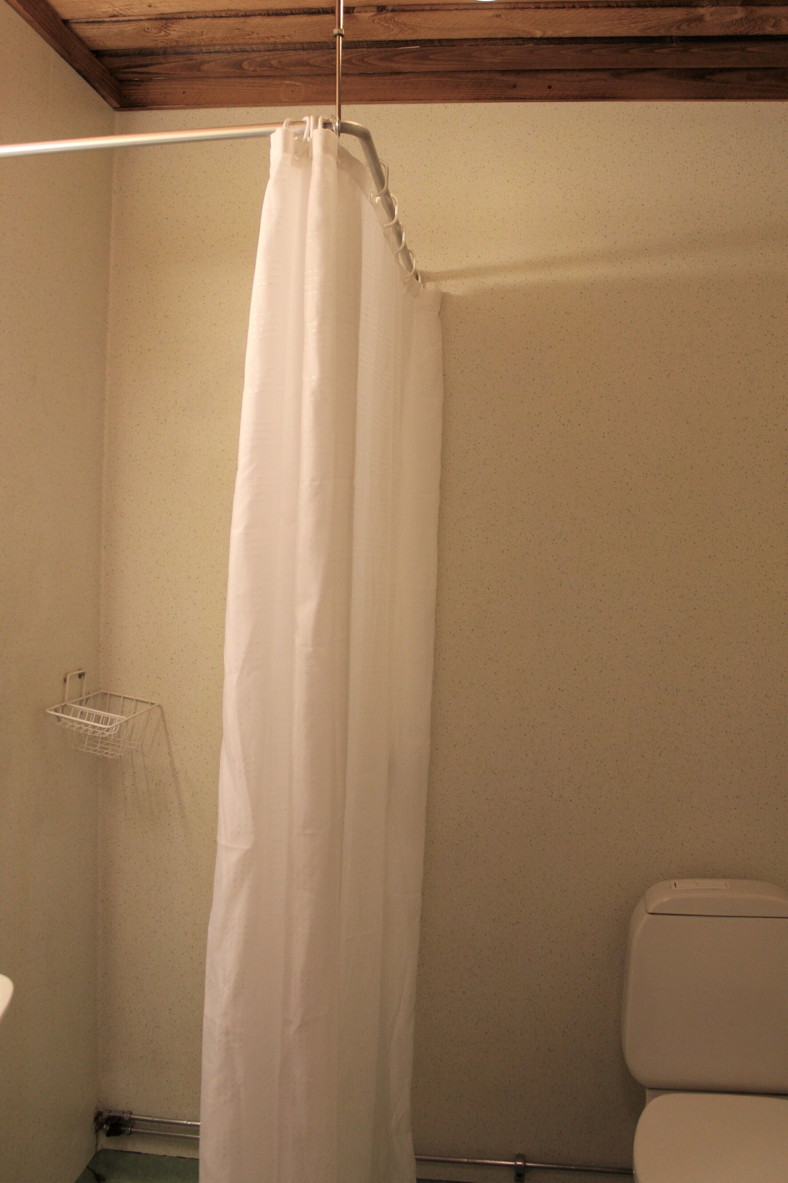 A bathroom with a shower curtain, a toilet, and a small metal rack.