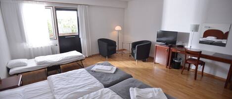 Ett hotellrum med två sängar, ett skrivbord, en stol, en tv och en lampa.
