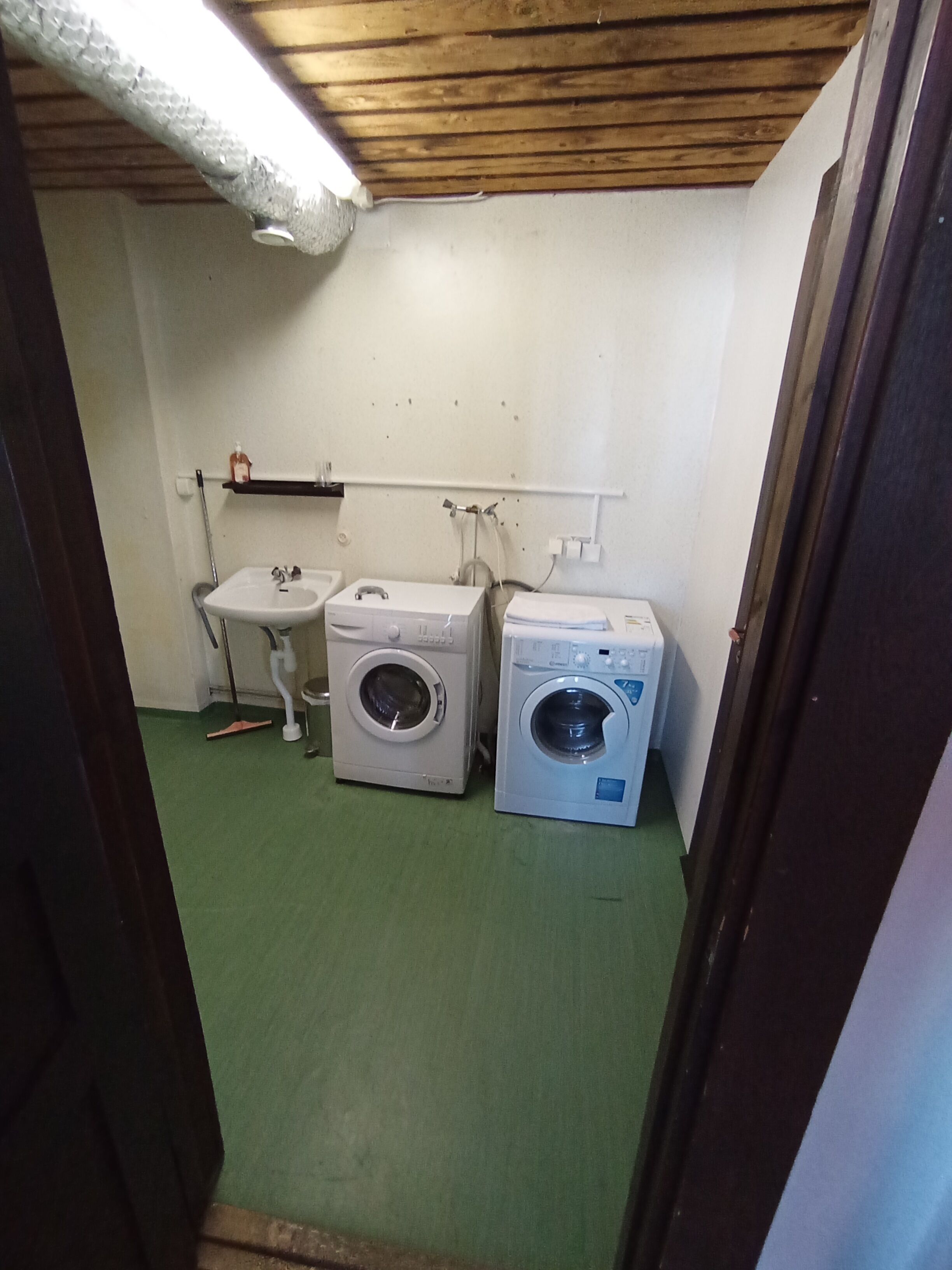 A laundry room with two washing machines, a sink, and a mop.