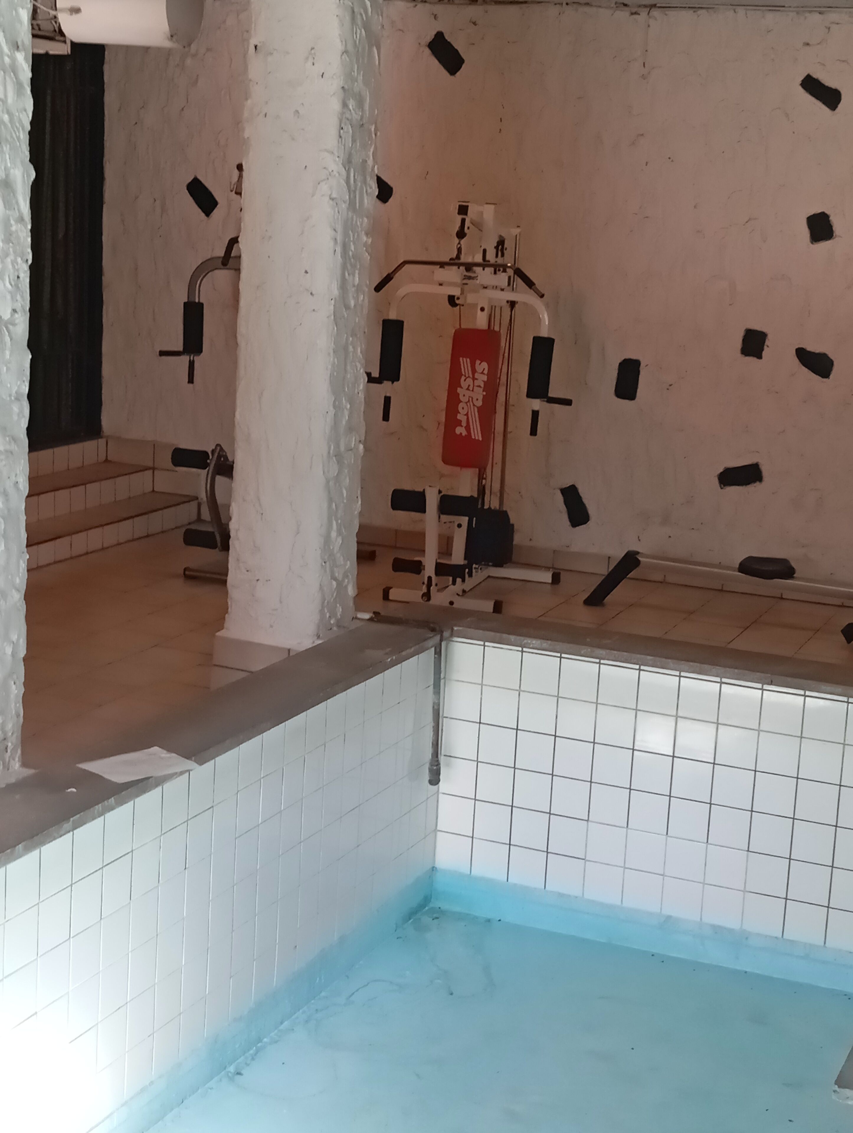 Ett badrum med ett kaklat golv, en vit pelare och en röd handduksställning.