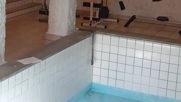 A bathroom with a tiled floor, a white pillar, and a red towel rack.