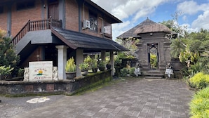 A hotel with a traditional design, a covered porch, and a small thatched-roof structure. - Hotel Bunga Permai (Ubud)