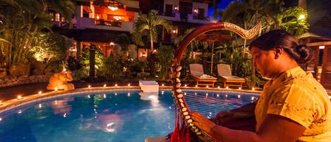 A poolside area with a traditional building in the background, a decorative headpiece, and a lit candle.