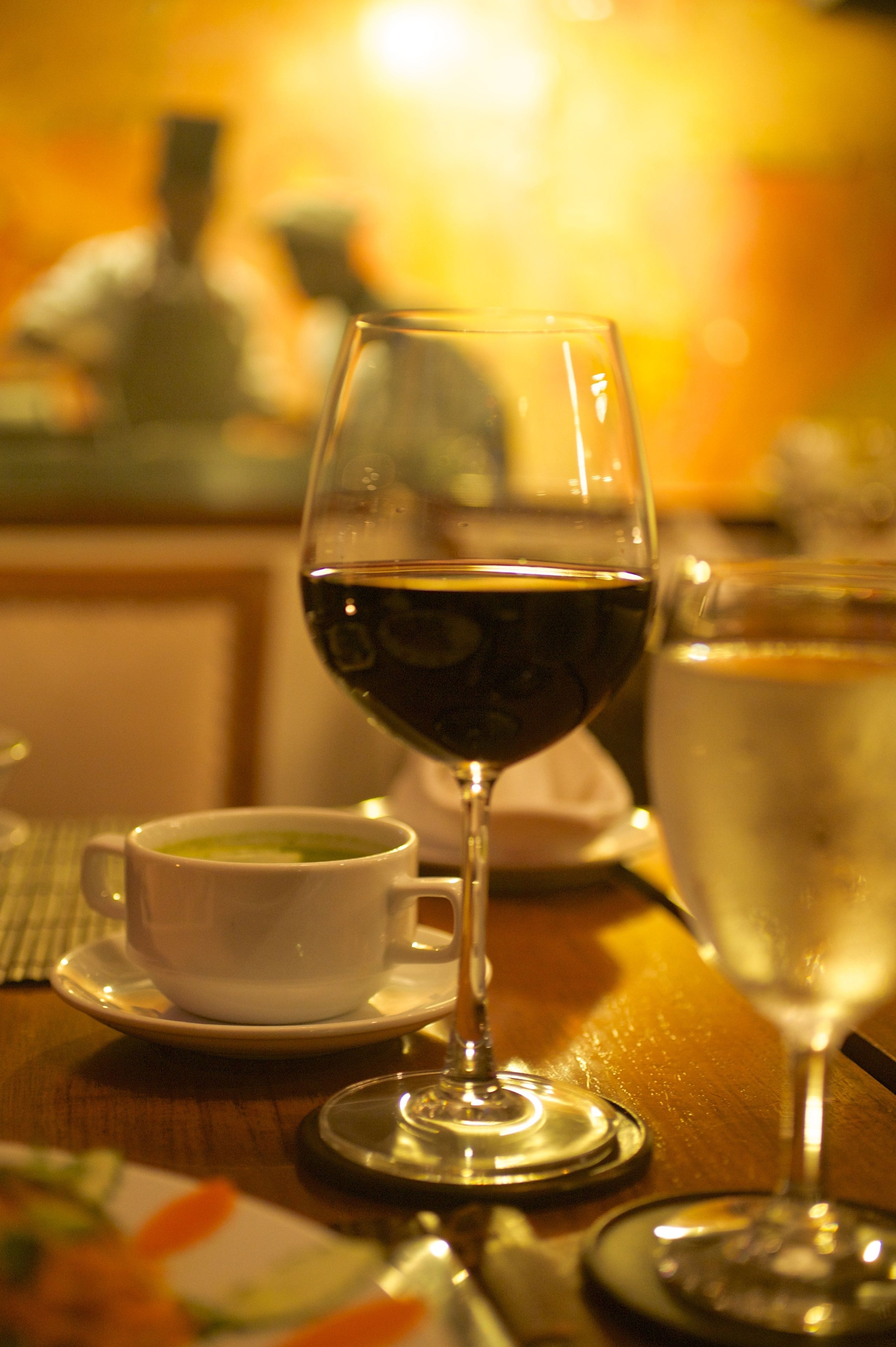 Een tafel met een wijnglas, een kopje thee en een glas water.