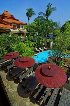 Relax by the serene pool surrounded by lush greenery and palm trees.