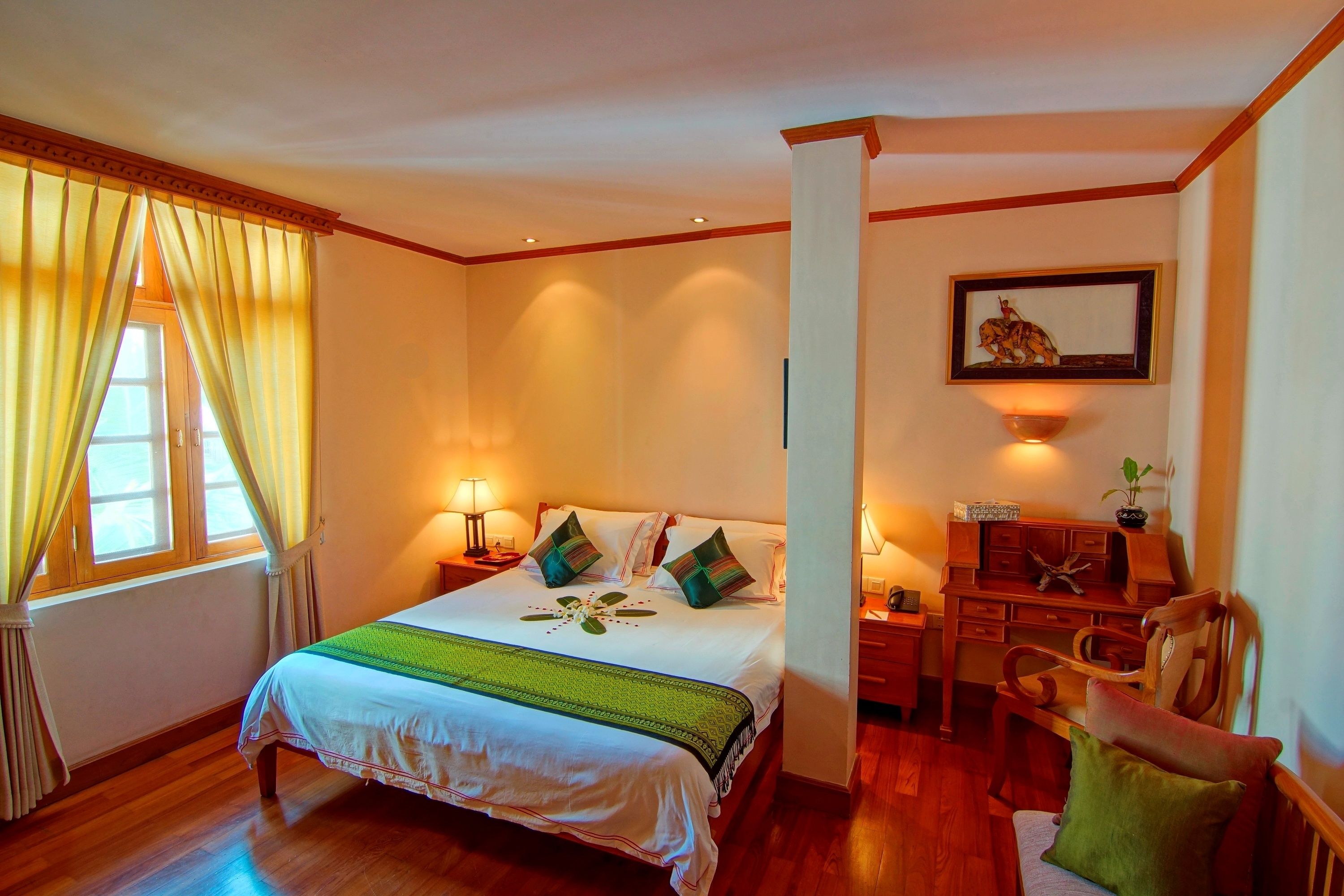 A neatly arranged bedroom with a bed, bedside tables, a desk, and a chair.