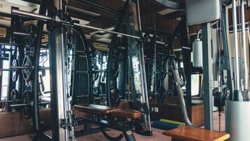 Un gimnasio con diferentes equipos de ejercicio, una banca y un espejo.