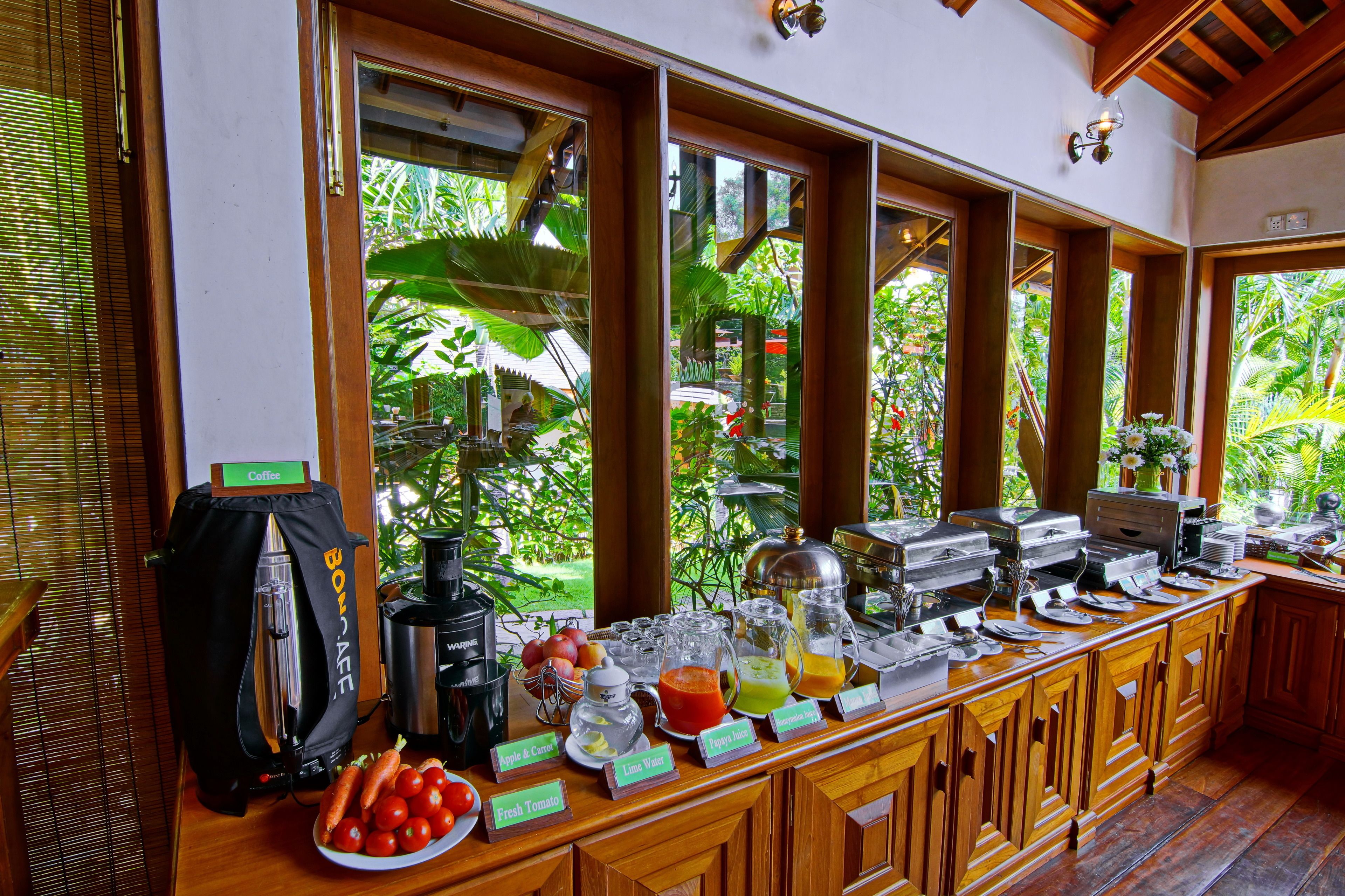 A buffet setup with various food and drink options, including fresh tomatoes, a coffee station, and a juice bar.