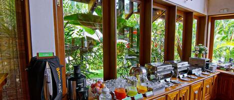 A buffet setup with various food and drink options, including fresh tomatoes, a coffee station, and a juice bar.