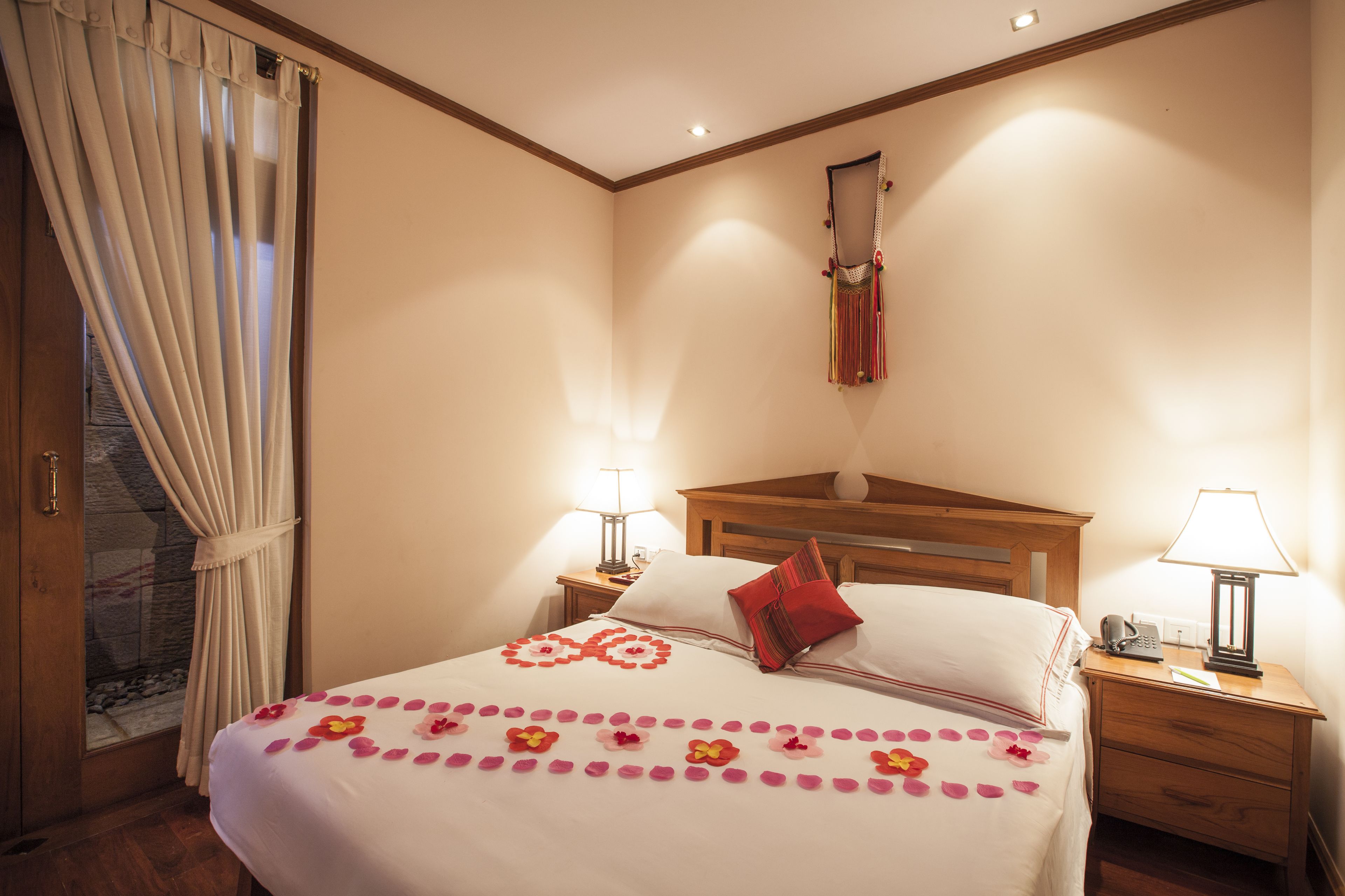 A hotel room with a large bed, two bedside tables, a wooden headboard, and a mirror on the wall.