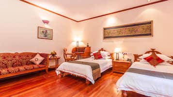 Habitación de hotel con dos camas, un sofá, un escritorio de madera y una lámpara de pared.