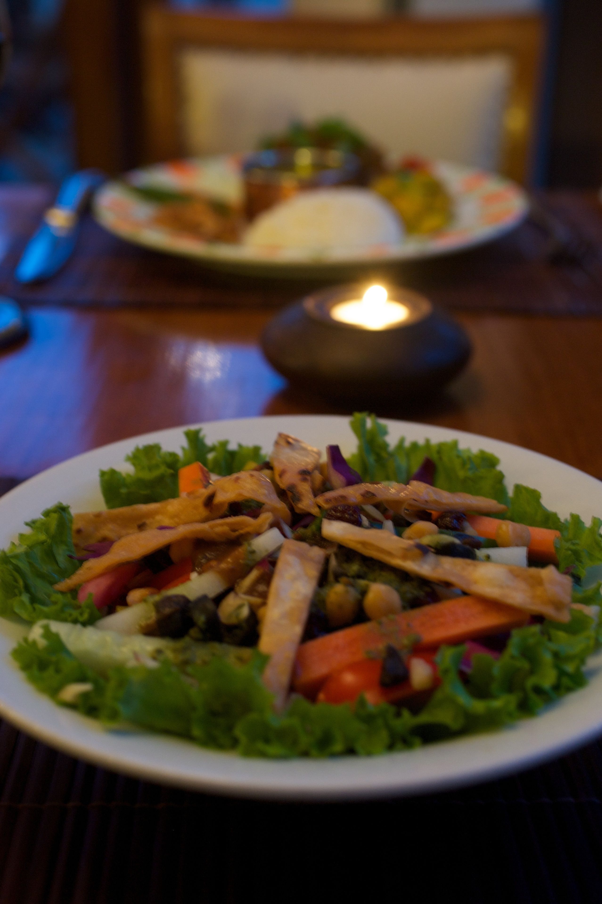 A plate of salad with various vegetables and grilled chicken pieces.