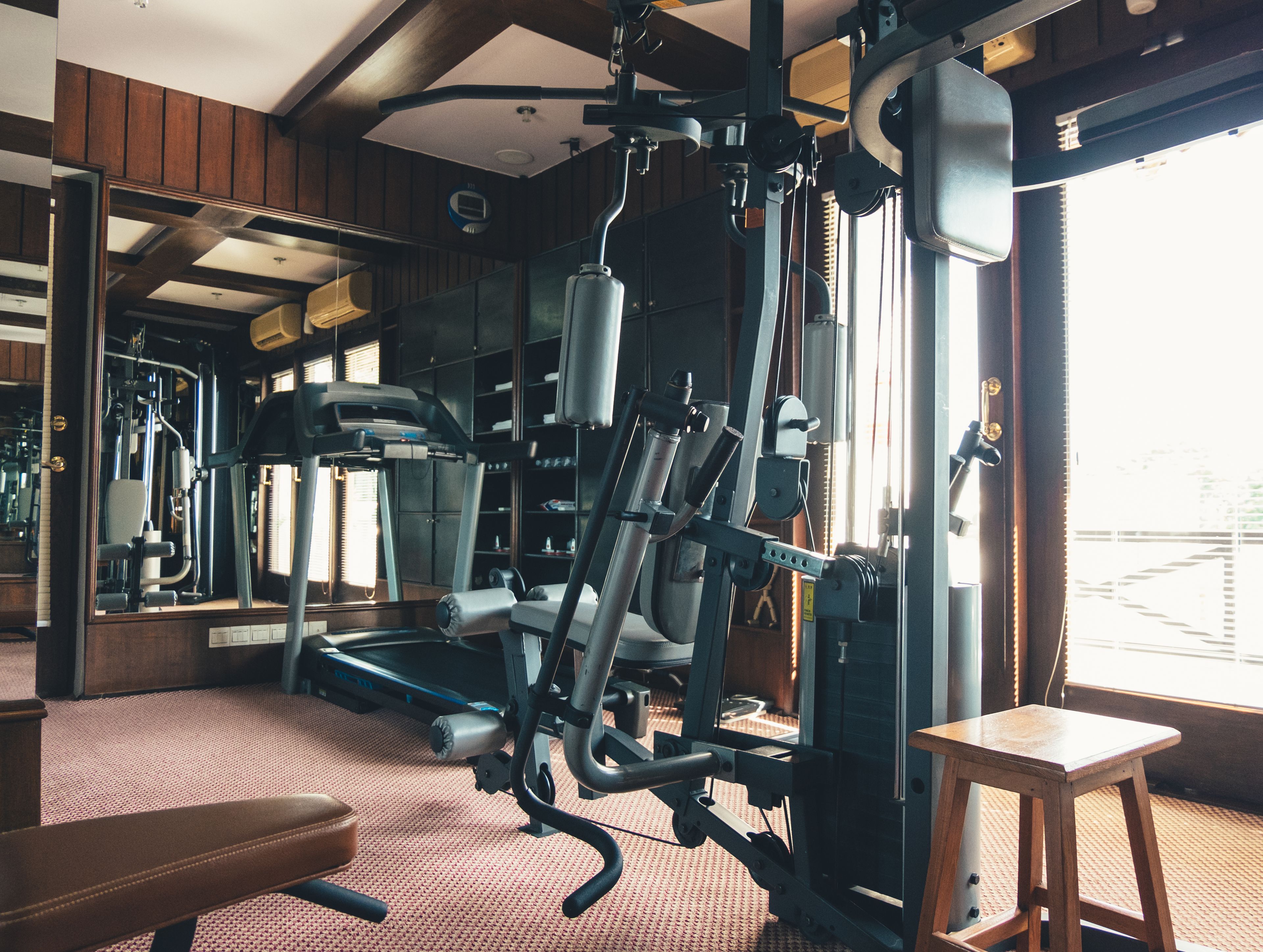 Une salle de sport équipée de matériel d’exercice, d’un tapis de course et d’un miroir.