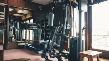 Une salle de sport équipée de matériel d’exercice, d’un tapis de course et d’un miroir.