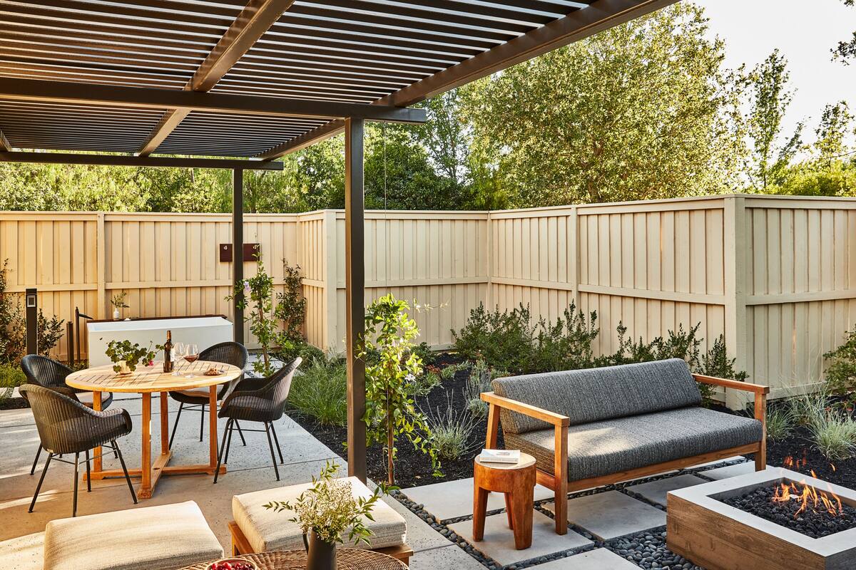 An outdoor patio area with a covered seating area, a fire pit, and a dining table with chairs.